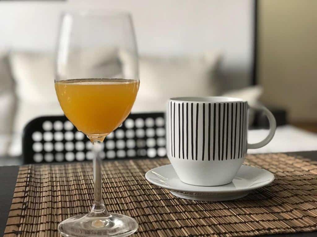 Elegant glass of orange juice and stylish striped mug on a dining table at Jacuzzi Views Málaga luxury apartment.
