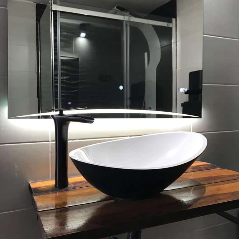 Luxury bathroom vessel sink with modern black and white design, illuminated mirror, and elegant wooden countertop.