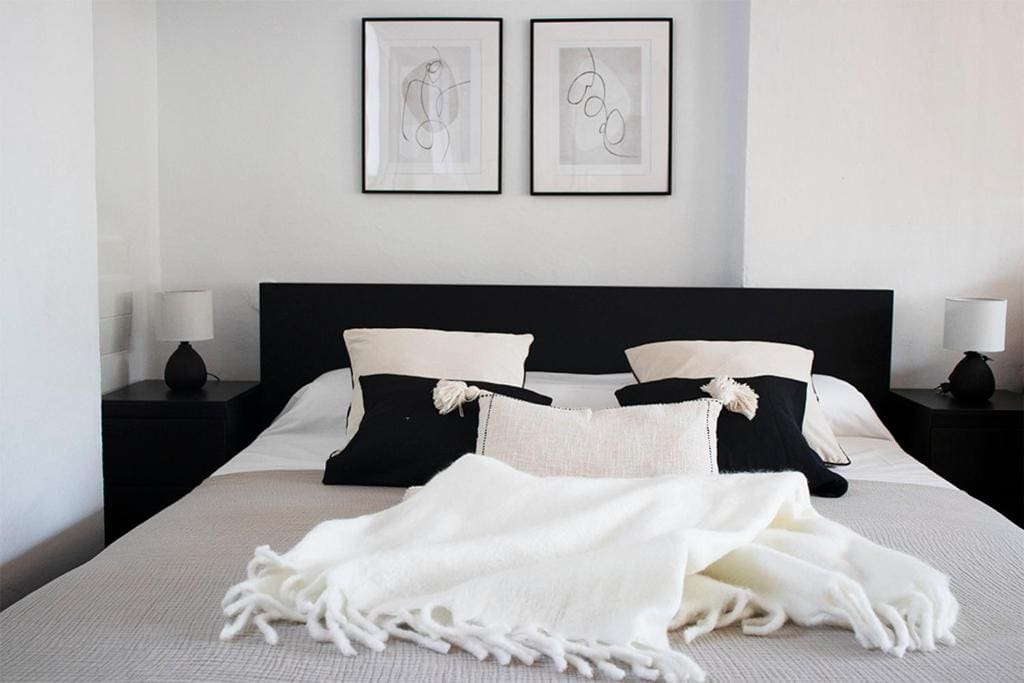Stylish bedroom in luxury villa with elegant black and white décor, perfect for a relaxing stay in Málaga.