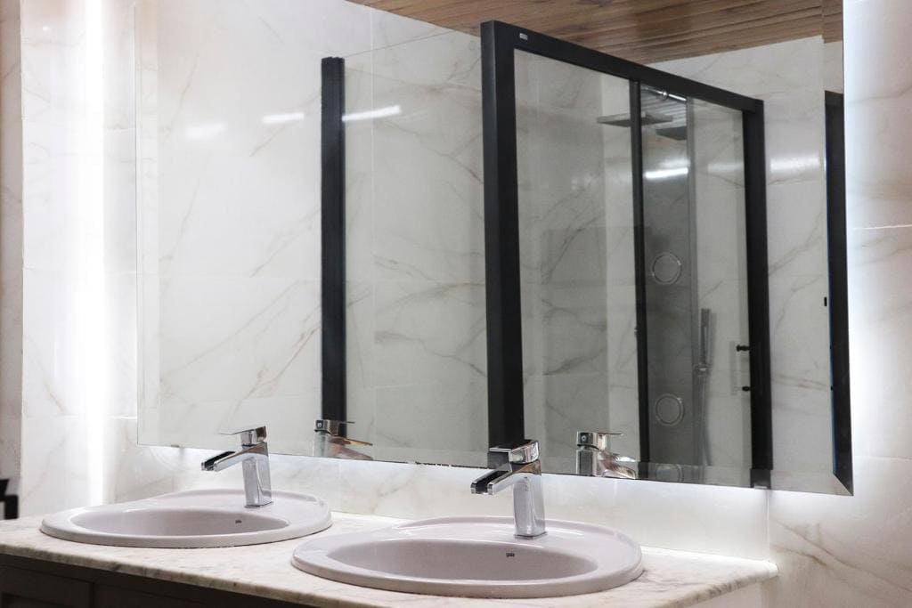 Modern double sink bathroom with marble counters and large mirror, stylish and functional.