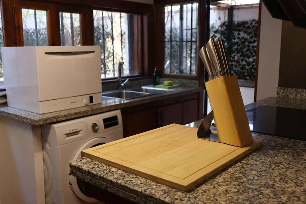 Clean kitchen with wooden knife block, granite countertops, and washing machine at Jacuzzi Views Málaga luxury villa