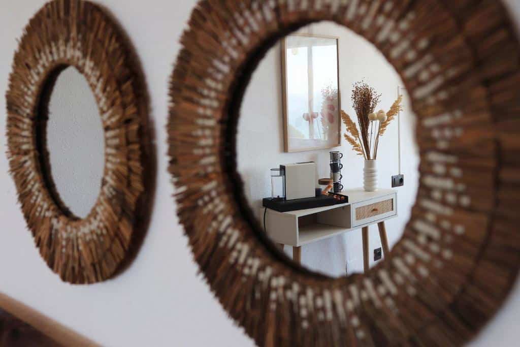 Reflective mirror with wicker frame in luxury villa interior, showcasing minimalist decor and natural elements.