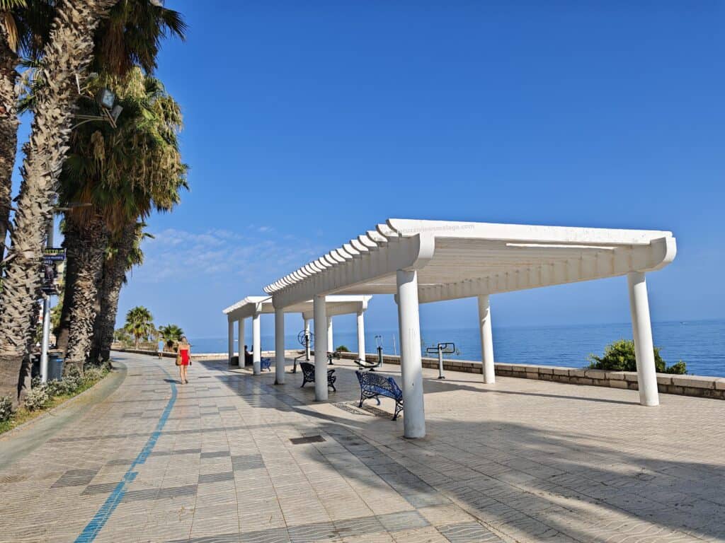 a walkway with benches and a couple of benches on a sunny day