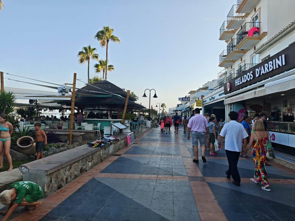 a group of people walking on a sidewalk carihuela promenade