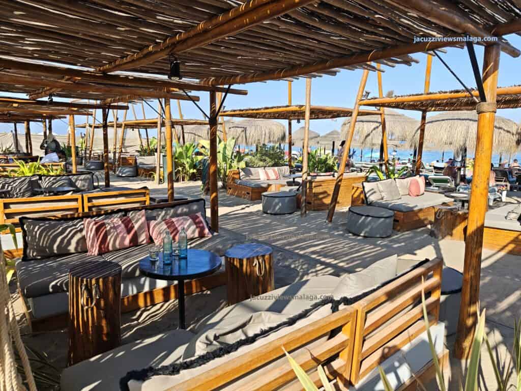 a beach bar with a wooden structure and chairs in los alamos beach