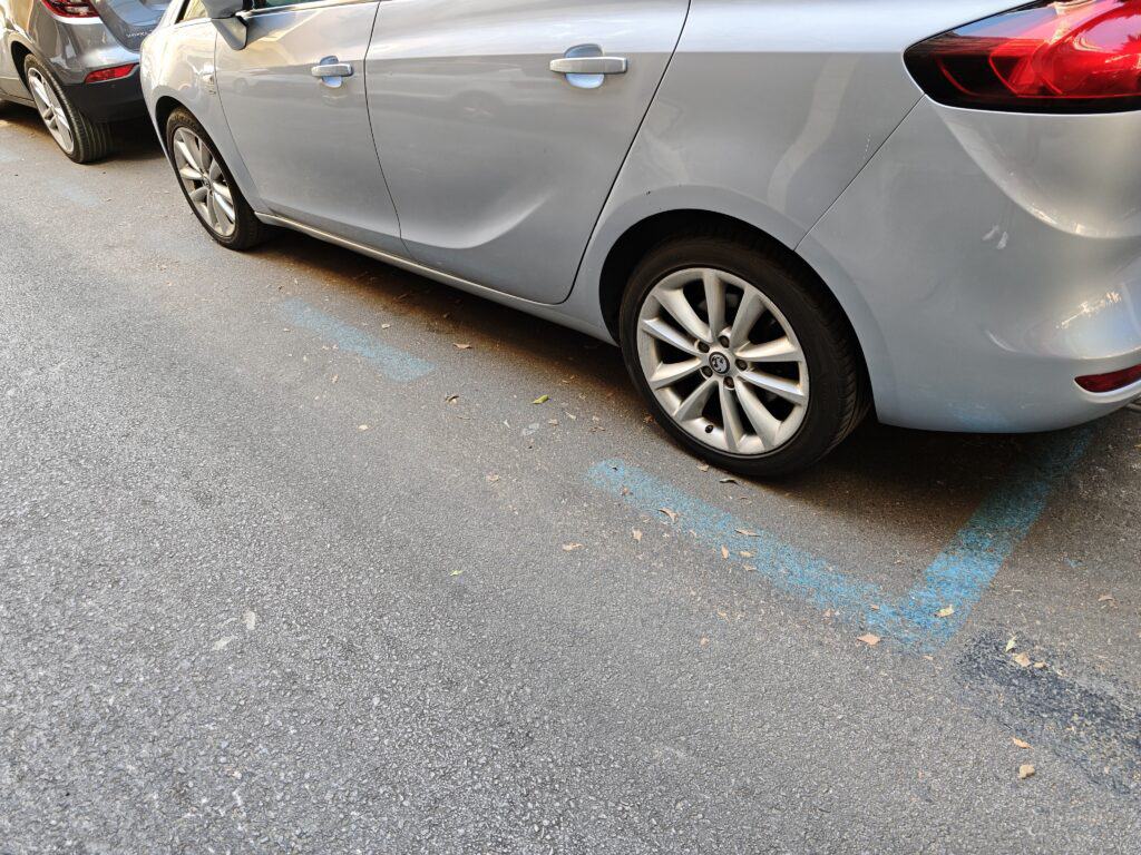 Empty parking spot in Málaga, with a silver car parked nearby.